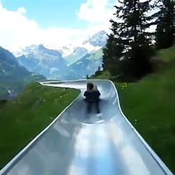 سرسره ای درتپه های سرسبز منظره کوه های برفی آلپ سوئیس هزینه این سرسره برای ب